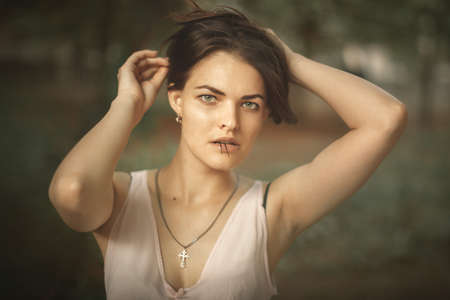 Vintage or retro portrait of young attractive girl pinning long hair with hairpins, holding one hairpin with her teeth and looking into camera.の写真素材