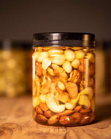 Farmer Honey mixed with nuts, seeds, dried fruits. Still life photography. Honey packaged in transparent jars with lids. Delicious healthy food. Closeup one Jar of honey with nut mixture.の写真素材