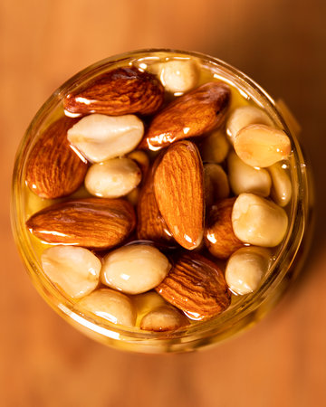 Honey mixed with nuts, seeds. Still life photography. Top view of an open round jar on wooden tableの写真素材