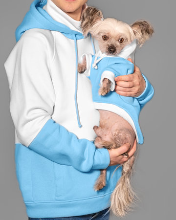 A young guy holds a Chinese Crested dog in his arms. Both wear the same clothes.の写真素材