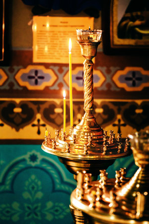 Interior of an Orthodox Ukrainian church. Burning candles on a gilded candlestick or candelabra.の写真素材