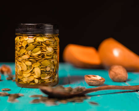 Pumpkin seeds and honey in jars on wooden blue color table in Rustic style. Autumn Season food photo.の写真素材