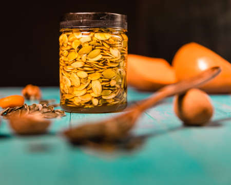 Pumpkin seeds and honey in jars on wooden blue color table in Rustic style. Autumn Season food photo.の写真素材
