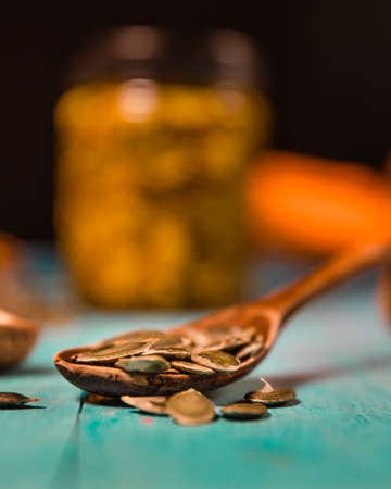Pumpkin seeds and honey ib jar on wooden blue color table in Rustic style. Autumn Season food photo.の写真素材