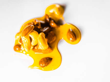 Honey mixed with nuts spilled on white surface.の写真素材