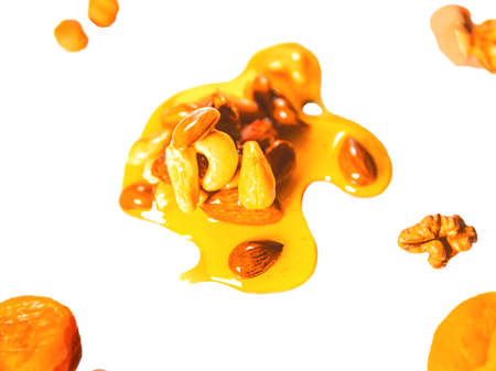 Pile or drops of honey mixed with nuts isolated on white background. Pattern. Healthy food.の写真素材
