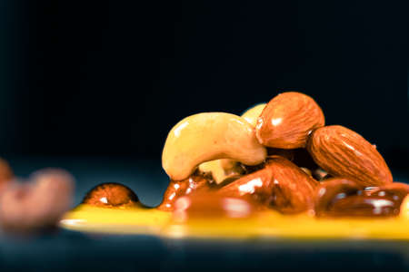 Honey mixed with nuts spilled on surface on black background,の写真素材