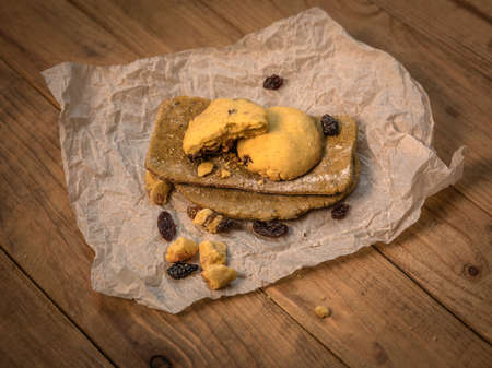 Made by hand fresh tortillas and cookies with raisins on parchment paper on wooden table. View from...