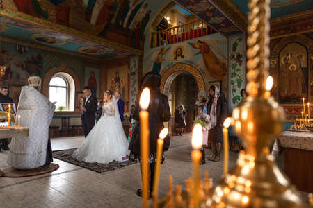 Pokrov, Ukraine - January 24, 2021:Church of St. John Chrysostom. Church wedding. Bride wearing a white dress and a veil and groom. The priest conducts the sacrament of the wedding in the temple.のeditorial素材