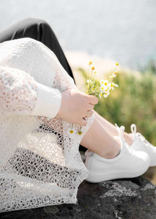Wedding couple man and woman in white shoes near river. People in love sitting together on hill, stone or rock at summer sunny day.の写真素材