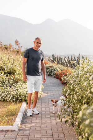 Portrait of a happy 60-year old man walking with his dogの写真素材