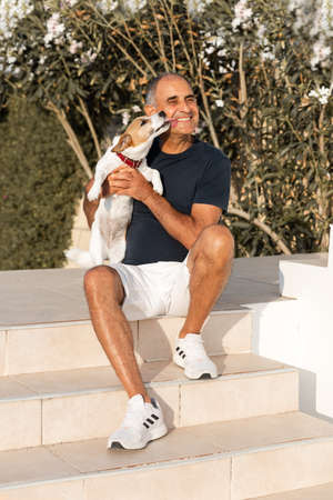 Portrait of happy 60-years old man and funny dog licking himの写真素材