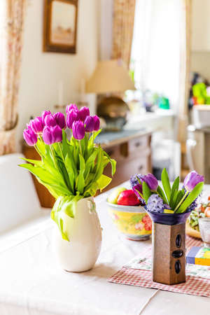 home interior decoration. Purple tulips flowers in vase on kitchen table next to window.の写真素材