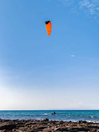 Person kiteboarding on sea waves on blue sky background. Kitesurfing Cyprus.の写真素材