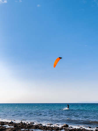 Person kiteboarding on sea waves on blue skyline background. Kitesurfing Cyprus.の写真素材