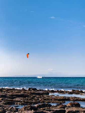 Person kiteboarding on sea waves neat coastline on blue sky background. Kitesurfing Cyprus.の写真素材