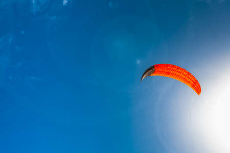 Bright orange color kite floating in air on blue sky background.の写真素材