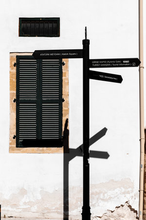 Nicosia, Northern Cyprus - June 28, 2022: Metal signpost near the wall of an old house with a window.のeditorial素材