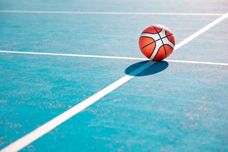 Orange basketball on the markup blue court outside. team sport concept. side view.の写真素材