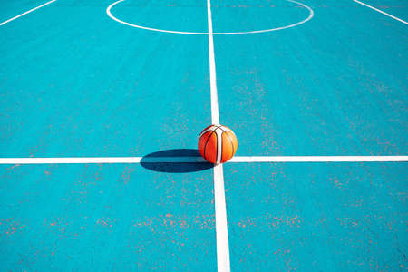 Orange basketball on the markup blue court outside. team sport concept.