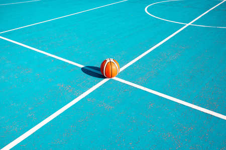 Orange basketball on the markup blue court outside. team sport concept.の写真素材