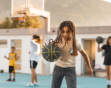 Northen Cyprus, Girne, Alsancak - Jule, 25, 2023: Basketball sport training on a basketball court outdoors. Portrait of 12-yars old girl running with ball.のeditorial素材