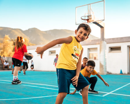 Northen Cyprus, Girne, Alsancak - Jule, 25, 2023: Basketball sport training for children teenagers around 7-14 years old on a basketball court oitdoors. Happy boy has a fun.のeditorial素材