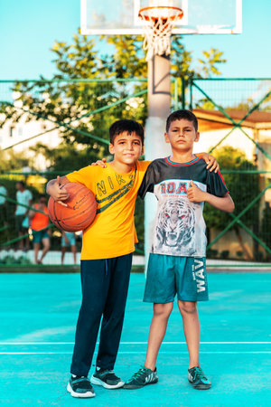 Northen Cyprus, Girne, Alsancak - Jule, 25, 2023: Two happy boys teenagers around 10 years old stand together on a basketball court at summer.のeditorial素材