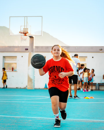 Northen Cyprus, Girne, Alsancak - Jule, 25, 2023: Basketball sport training on a basketball court outdoors. Portrait of 15-yars old young girl running with ball.のeditorial素材