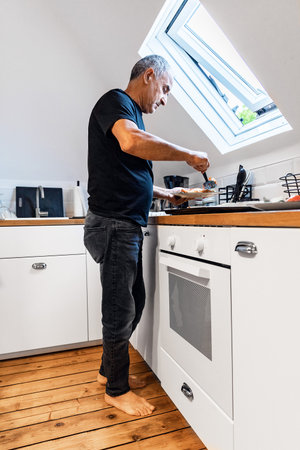 Senior Man Serving Baked Food at Home in Modern Kitchen During Daytimeの写真素材