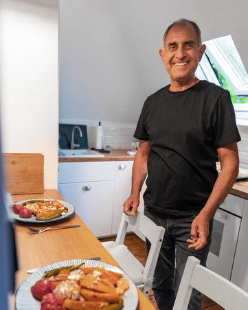 Smiling Senior Man Serving Healthy Homemade Vegetarian Meal for Twoの写真素材