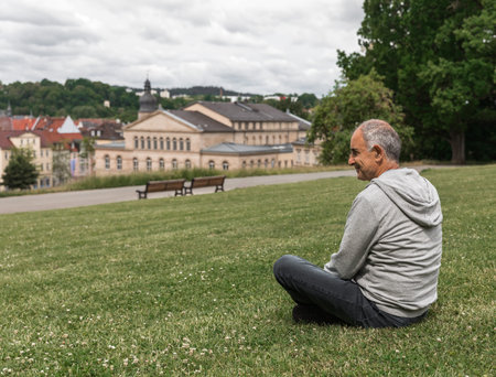 Senior man sitting in profile with panoramic view of Ehrenburg Palace and Altes Zeughaus in Coburgの写真素材