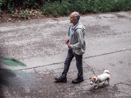 Senior man walking with Jack Russell terrier on pedestrian alley, active healthy lifestyleの写真素材