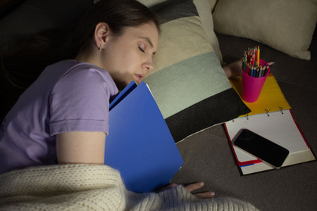 Young woman sleeping among notebooks and stationeryの写真素材
