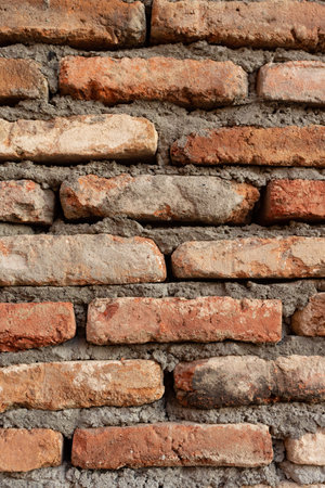 Texture of old brickwork with holes. Dark red brick wall in the old city. Vertical photo close upの写真素材