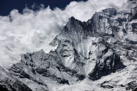 snow mountains against white clouds and blue skyの写真素材