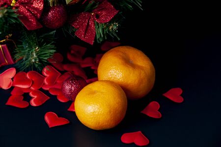 Tangerines red hearts bows under a Christmas tree on a dark backgroundの写真素材