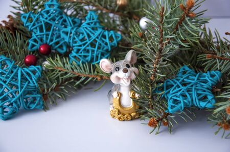 Christmas rat on the background of Christmas tree branches of red and silver balls, blue stars.の写真素材