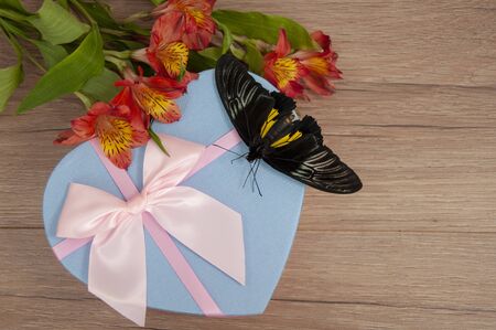 Big beautiful exotic butterfly, flowers, gift and on a wooden background. Butterfly troides rhadamantusの写真素材