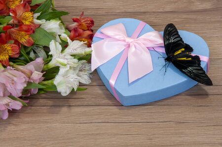 Big beautiful exotic butterfly, flowers, gift and on a wooden background. Butterfly troides rhadamantusの写真素材