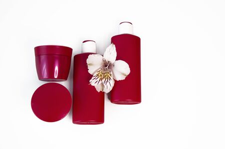 Cosmetic products on a white background. Red bottles and jars, moose, tonic, cream. Copy space for textの写真素材