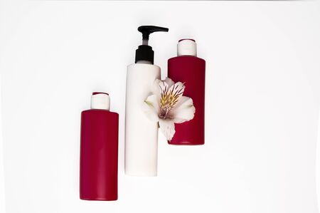 Cosmetic products on a white background. Red bottles and jars, moose, tonic, cream. Copy space for textの写真素材