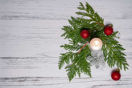 Christmas tree, red bauble balls and a candle on a light wooden background.の写真素材