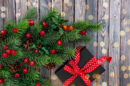 Decorated branches of a Christmas tree, cones, red berries and gifts on a wooden table. Christmas decor.の写真素材