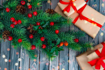 Decorated branches of a Christmas tree, cones, red berries and gifts on a wooden table. Christmas decor.の写真素材