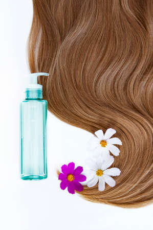 Healthy and beautiful hair. Cosmetic oil and flowers for hair on a white background. Hair care. Copy space for textの写真素材