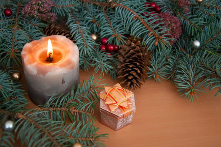 Christmas background. Christmas tree branches, cones, gift, balls, candle on wooden texture