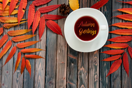 White cup of natural tea with rose hips on a wooden background with autumn leaves. Autumn lifestyle....