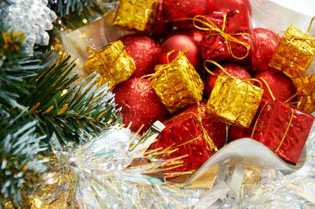 Christmas composition with Christmas tree branches, red balls on yellow gifts in silver tinselの写真素材