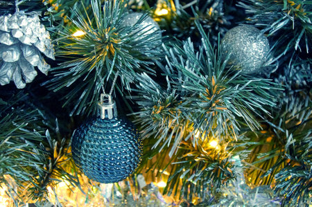 Christmas background with Christmas tree branches, blue ball, silver tinsel in the light of golden garlandの写真素材